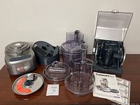 Full view of all components including base unit, bowls, lids, feed tubes, blade storage, and manuals.