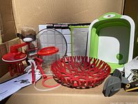 Photo showing the various kitchen items including Tupperware Power Chef whip accessory parts, green collapsible wash basin, red woven decorative bowl, splatter screen, thawing plate, and others.