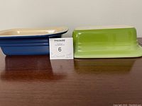Side view of two Le Creuset loaf pans, one blue and one green, showing their rectangular shape and cream interiors