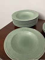 Stack of 8 green Pfaltzgraff bowls with a close-up of the chip on one bowl.