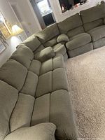 View of green sectional couch with cushioned seats and backrests in L-shape configuration.