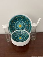 Melamine salad set including one large serving bowl, nine smaller salad bowls, and two glass dressing bottles with white lids and pour spouts, all arranged on a table.