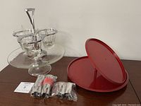 Clear glass condiment server with four dipping cups and a red cake plate with various shape cutters laid out