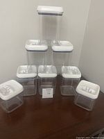 Eight clear plastic storage containers arranged in pyramid shape; six larger containers with white lids on bottom and two taller containers with white lids on top.