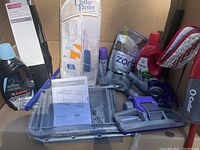 Image showing multiple items including the Delta towel rack packaging, O-Cedar spray mop with red microfiber pads, Clutter Buster hanging organizer, and various parts and bottles of cleaning supplies.