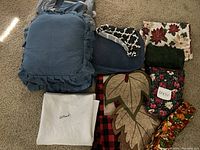 View of blue chair cushions, floral table runners, and various folded cloths including white pieces.