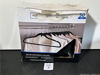Box of 50 Mainstays felt hangers with visible box damage and product labeling.