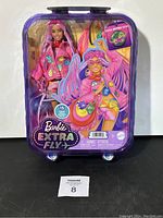 Front view of Barbie Extra Fly 15 Pieces doll in suitcase-style packaging showing doll, accessories, and artwork.