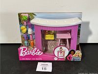 Front view of Barbie Smoothie Bar in packaging, showing pink bar, stool, yellow boombox, and smoothie accessories on the left.