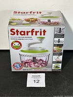 Photo of Starfrit Duel Speed Pro Food Processor in original box. Box front shows the food processor bowl with vegetable contents, with green and white lid, highlighting new blades and dual speed functionality.