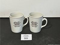 Two white ceramic Tim Hortons coffee mugs side by side showing front logo and handles.
