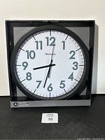 Front view of Westclox 14-inch wall clock in packaging with clear number markings and black frame.