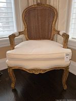 Front view of gilt bergère armchair with white cushion