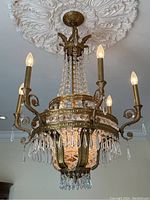 Chandelier hanging beneath decorative ceiling medallion, showing full fixture and six lit bulbs