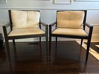 Front view of both chairs side by side showing dark wood frames and cream cushions
