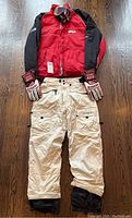 Full outfit laid out on wood floor: jacket, pants and gloves