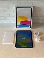 Box, iPad tablet, USB-C cable, power adapter and documentation arranged on countertop