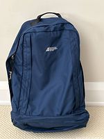 Front view of navy blue Mountain Equipment Co-op hiking bag showing logo and zipper pocket