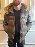 Model wearing olive green Dolce & Gabbana down puffer jacket, front view showing ribbed cuffs and hem, zip closure, side pockets