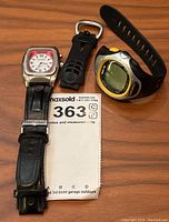 Overview of two watches on wooden surface with lot tag visible
