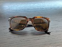 Front view of tortoiseshell acetate Persol sunglasses on wooden surface