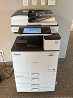 Front view of the Ricoh MP C3003 showing four paper trays and automatic document feeder