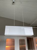 Rectangular white acrylic pendant light suspended from ceiling showing full view