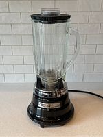 Full view of blender with glass pitcher and lid showing ribbed glass design and handle.