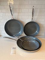 Set of four Zwilling J.A. Henckels frying pans displayed front-facing showing the non-stick cooking surfaces and handles.