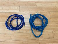 Photo showing two bike lock chains side by side on a wooden floor. One is dark blue and about 9.5 feet long, the other is aqua blue and about 12 feet long. Both chains have a rubberized coating and come with a mini-padlock attached.