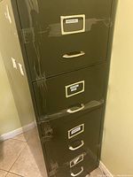 Photo showing brown metal filing cabinet with 4 drawers taped shut for transport. Labels on drawers visible.