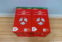 Top view of stacked unopened Staples copy paper reams showing front packaging with FSC certification and paper specifications.