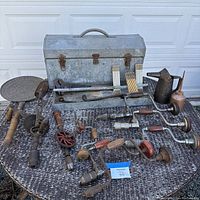 Full view of metal toolbox with variety of vintage hand tools including drills, wrench, oil cans.