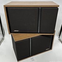 Pair of Bose 301 Series III bookshelf speakers stacked with wood grain finish and black grills, displaying front and side views.