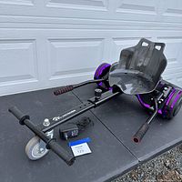 Evercross hoverboard attached to the black metal frame go-kart seat, showing overall assembled setup including padded handles and front caster wheel.