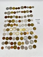Photo showing front view of all 100 assorted coins laid out in organized rows on a white background.