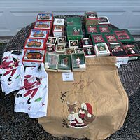 Wide view showing all the holiday ornaments boxes arranged with Santa-themed fabric items and the tan stocking laid out on a table.