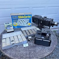 Full lot overview showing projector, slide sorter box, slide organizers, viewers, and accessories.