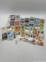 Top view of assortments of Pokémon trading cards in protective sleeves spread out on a flat surface.