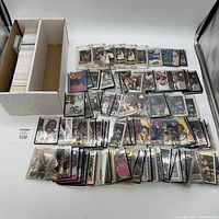 Overview of white storage box with divider and numerous sports cards laid out on table