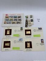 Photo showing assorted souvenir train stamps on sheets and strips along with first day of issue envelopes featuring gold-tone stamps depicting different historical themes.