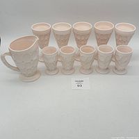 Full lot of the pink milk glass collection including the pitcher, five goblets, and five smaller cups.