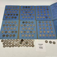 Open coin books showing multiple Jefferson nickels mounted in blue pages with years and mint marks from 1938 to 1961, partially incomplete.