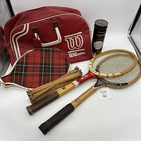 Overview photo showing the three vintage wooden tennis rackets, wooden racket press, a red Wilson tennis bag, and the can of Dunlop tennis balls.