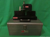 Photo of Craftsman black plastic mitre box placed on top of the closed metal toolbox with Craftsman badge visible on both.