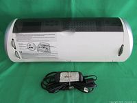 Closed view of white Cricut CREX001 cutting machine with attached AC power cord coiled in front.