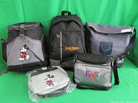 Five assorted Disney bags including Mickey Mouse backpack, Seven Dwarfs Mine Train backpack, Pandora shoulder bag, EPCOT lunch bag, and Mickey Mouse fanny pack.