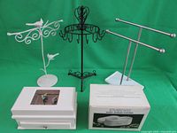 Three metal jewelry racks in black and white on green background with boxed Inverness Sonic Jewelry Cleaner.
