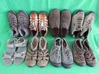 Front view of all shoes and sandals lined up on green cloth background.