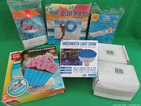 All items in lot with original packaging and boxes, showing variety of pool floats and lights.